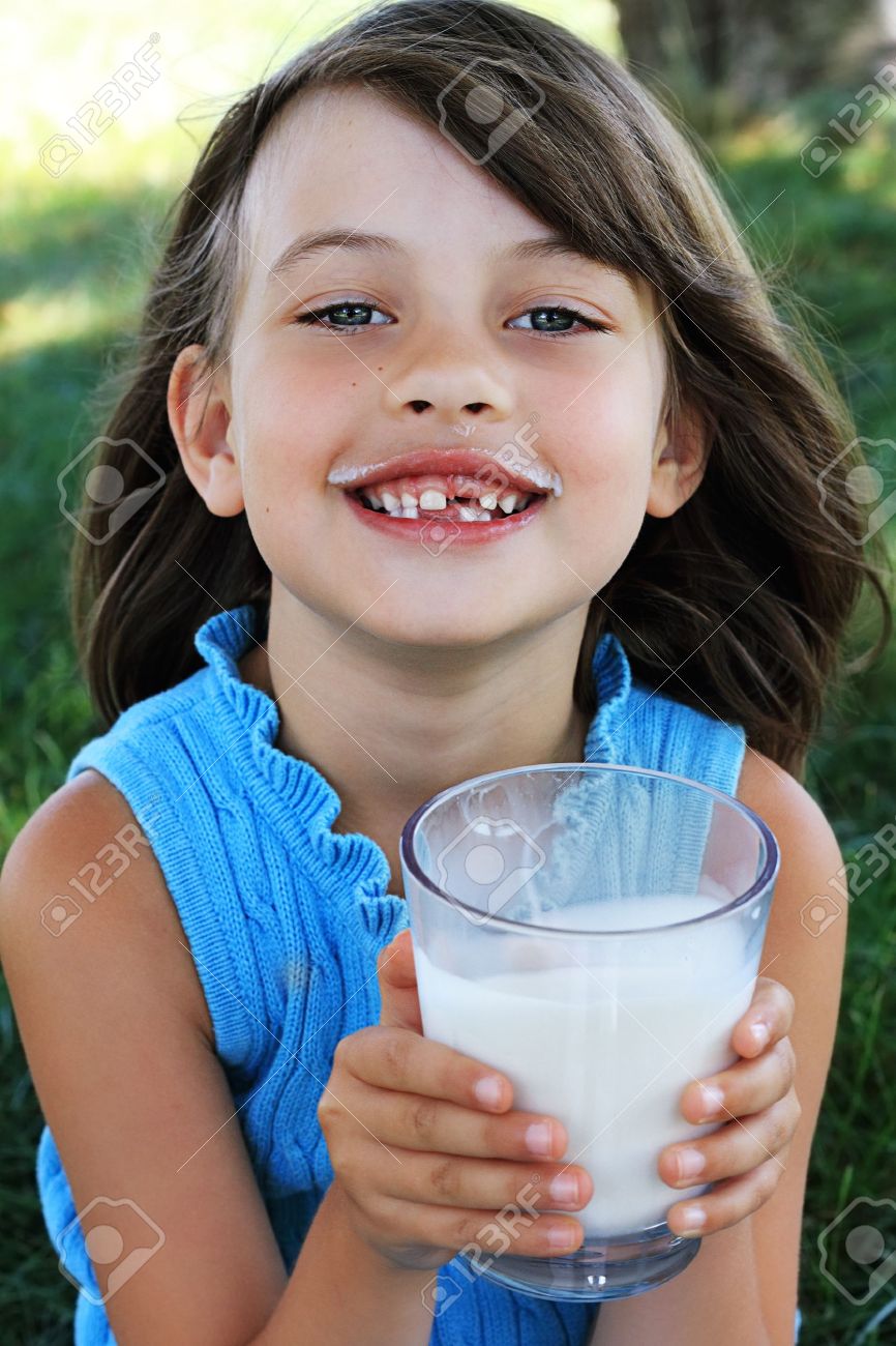 小さな女の子がミルクの口ひげで牛乳を飲みます 少女の顔の選択的な焦点とフィールドの浅い深さ の写真素材 画像素材 Image