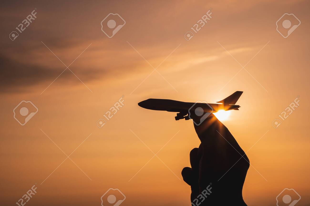 A hand holding a toy plane Go to the sky with sunset light - 142227698 A hand holding a toy plane Go to the sky with sunset light - 142227698