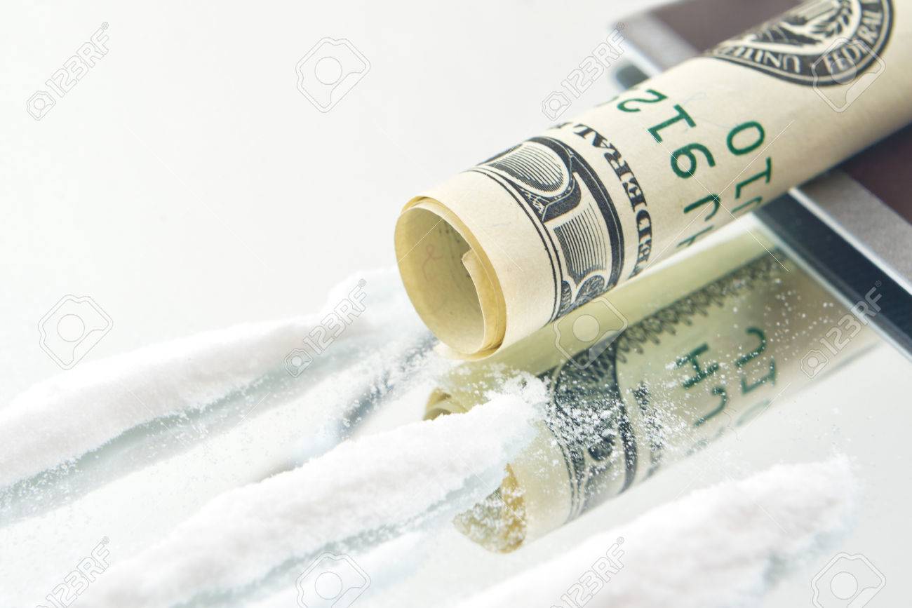 cocaine drug powder lines and rolled up usa hundred dollar bill