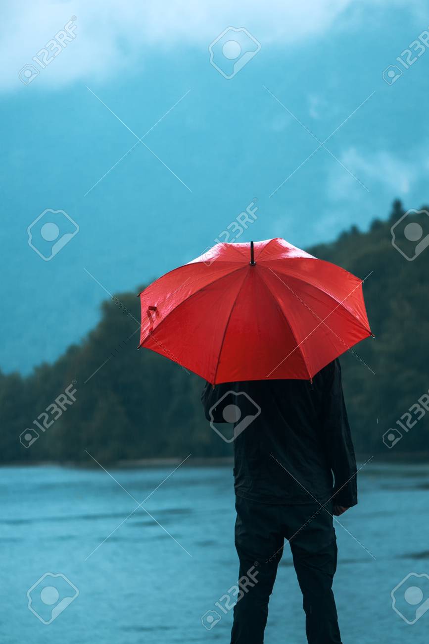 赤い傘を持つ男は 湖の前で雨に意図しています 悲しく 孤独な男性の人は距離に探しています の写真素材 画像素材 Image
