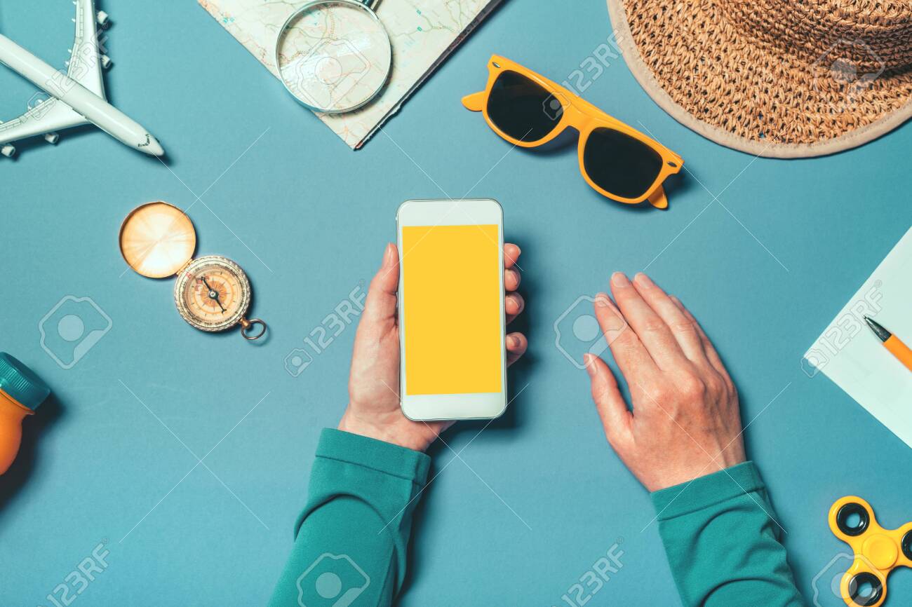 Smartphone mock up in summertime holiday vacation concept, woman holding mobile phone with blank screen as copy space, top view overhead shot with flat lay arranged summer accessories - 123224159 Smartphone mock up in summertime holiday vacation concept, woman holding mobile phone with blank screen as copy space, top view overhead shot with flat lay arranged summer accessories - 123224159