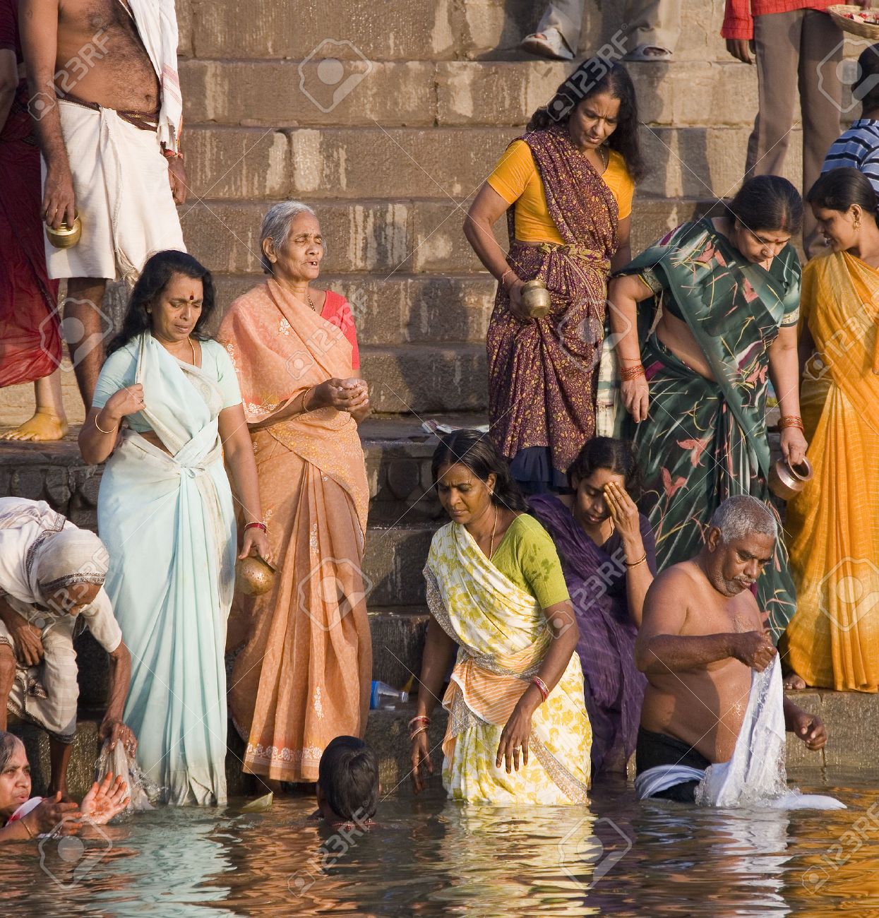 Group of pilgrims on the Hindu ghats on the banks of the Holy River Ganges (Ganga) in Varanasi (Benares) in the Uttar Pradesh region of northern India. - 22358553 Group of pilgrims on the Hindu ghats on the banks of the Holy River Ganges (Ganga) in Varanasi (Benares) in the Uttar Pradesh region of northern India. - 22358553