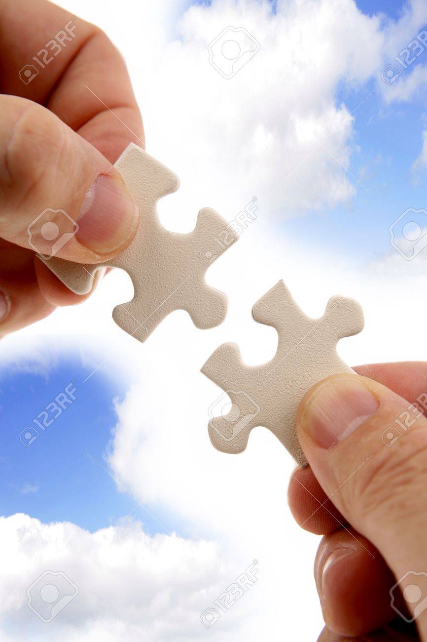 指は 青い空の前に 2 つのパズルのピースを保持しています の写真素材 画像素材 Image