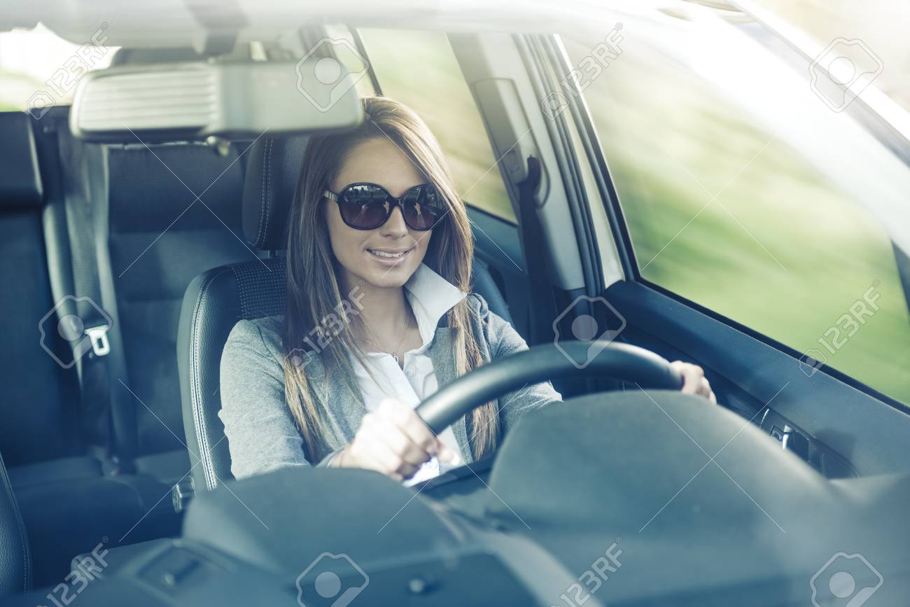 魅力的な女性 サングラスを身に着けている彼女の車を運転し 笑みを浮かべてします の写真素材 画像素材 Image