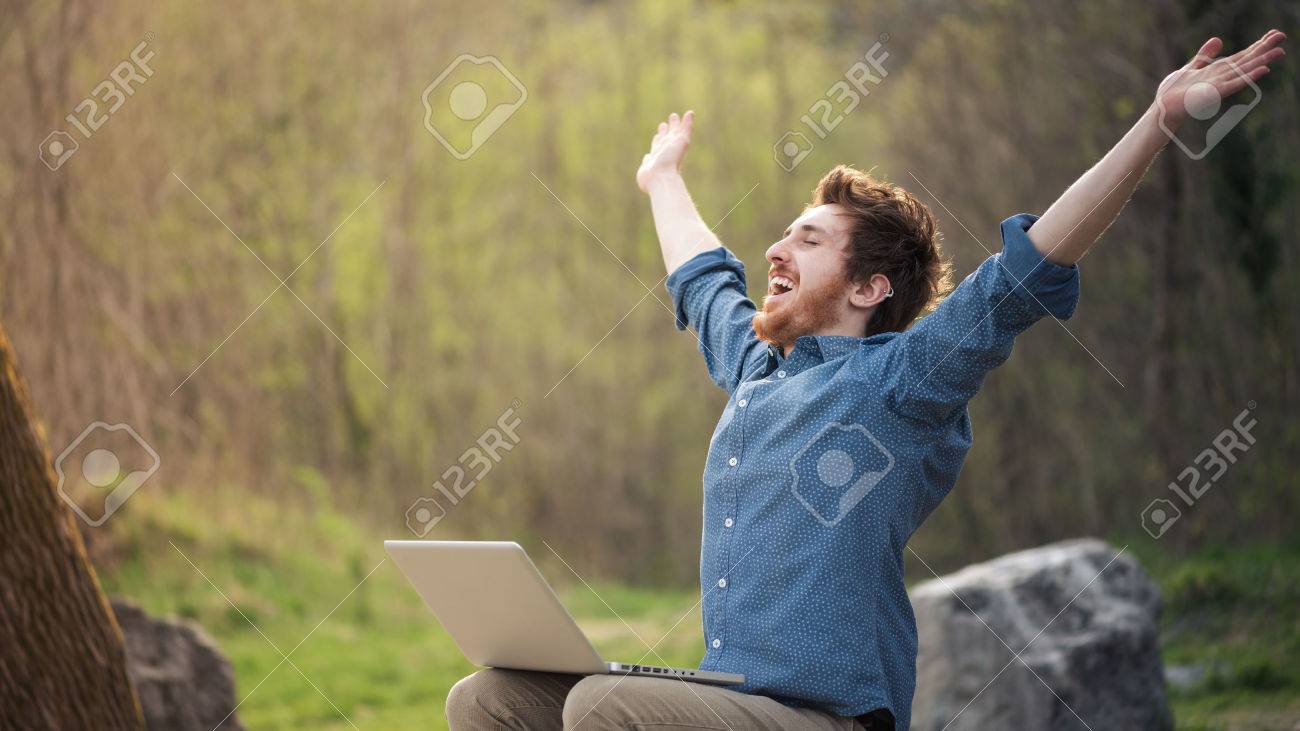 Happy cheerful man with a laptop sitting outdoors in nature, freedom and happiness concept - 41802498 Happy cheerful man with a laptop sitting outdoors in nature, freedom and happiness concept - 41802498