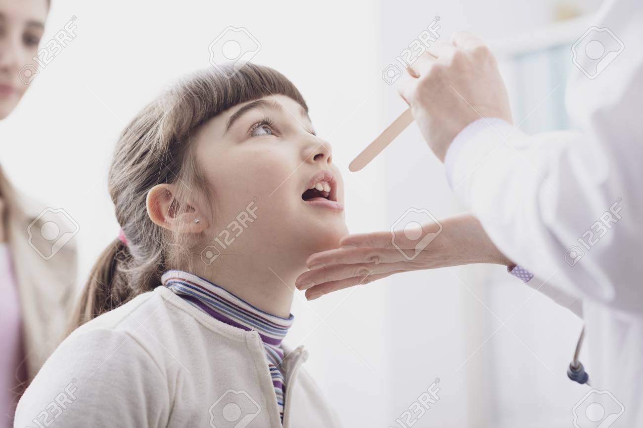 Professional doctor checking a girl's throat, she is opening her mouth - 122845750 Professional doctor checking a girl's throat, she is opening her mouth - 122845750