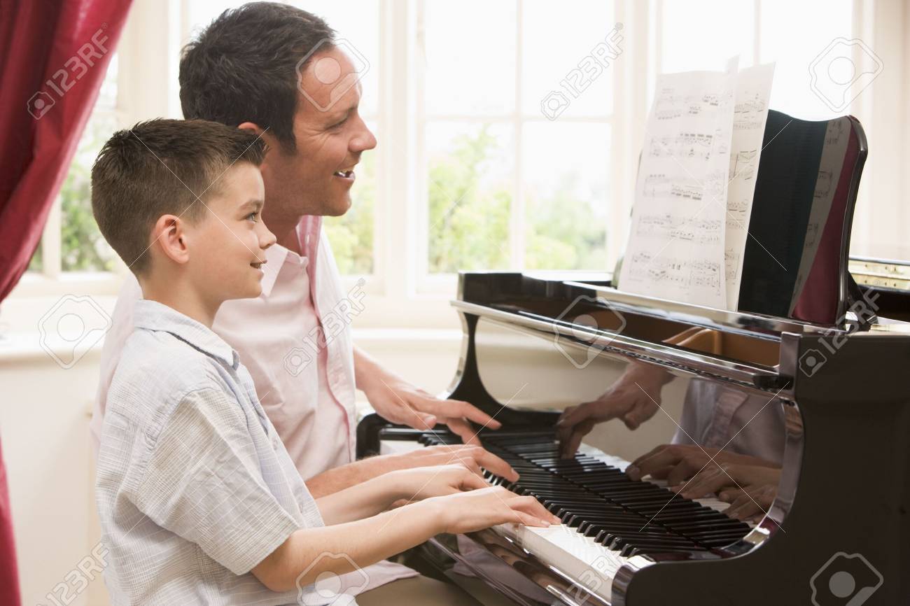 Man and young boy playing piano and smiling - 3601355 Man and young boy playing piano and smiling - 3601355