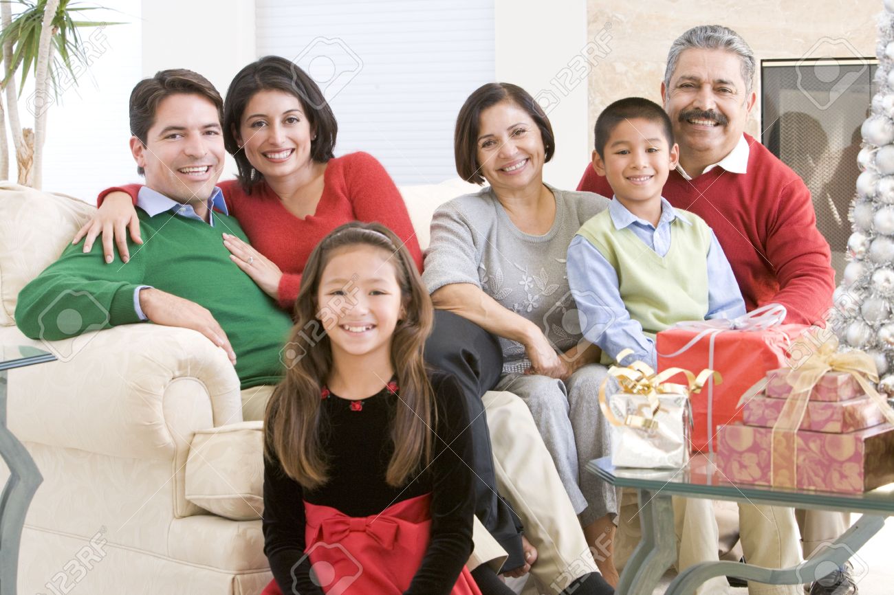 family sitting around a coffee table and christmas gifts stock photo