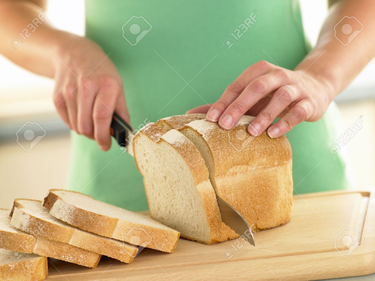 woman slicing a loaf of white bread stock photo picture and royalty