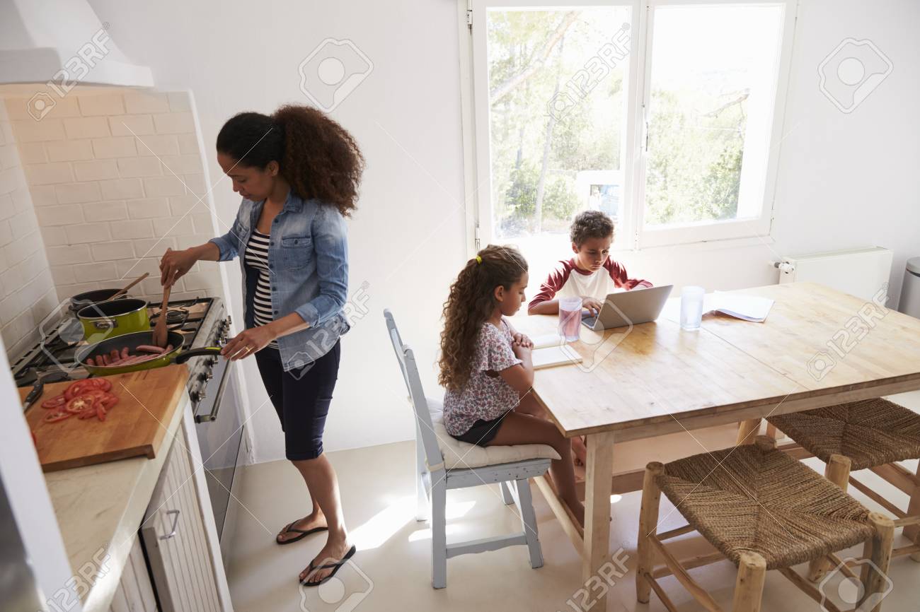 Mamá Cocinando Mientras Los Niños Trabajan En La Mesa De La Cocina ... Mamá Cocinando Mientras Los Niños Trabajan En La Mesa De La Cocina ...