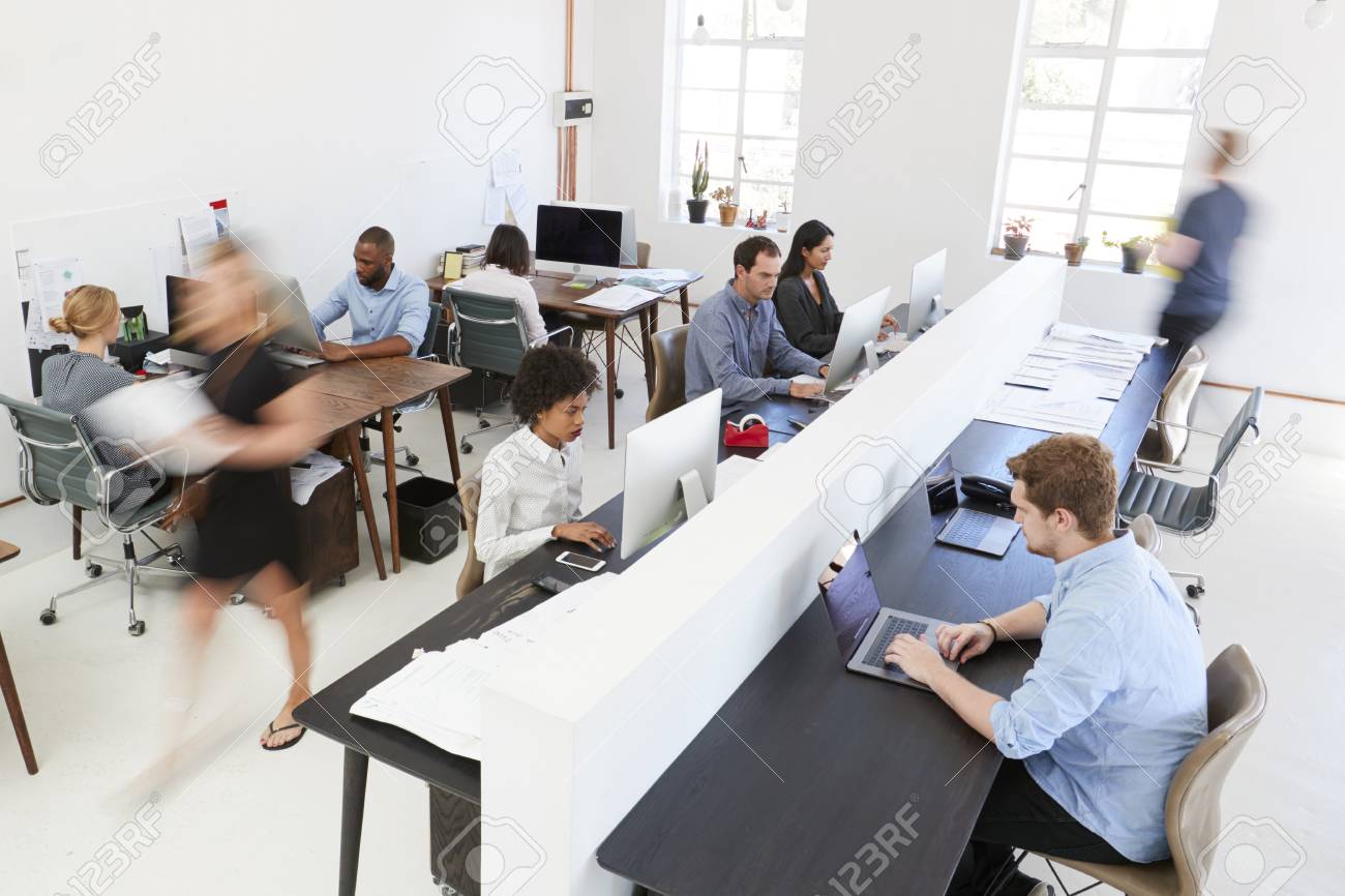 Young colleagues at computers in a busy open plan office - 85280433 Young colleagues at computers in a busy open plan office - 85280433