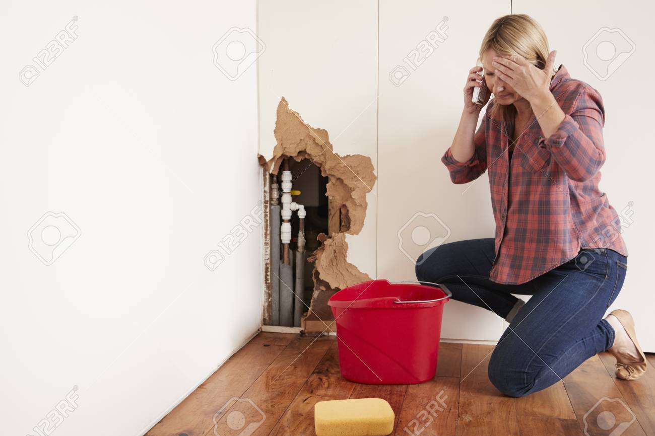 Middle aged woman with a burst water pipe phoning for help - 91579671 Middle aged woman with a burst water pipe phoning for help - 91579671