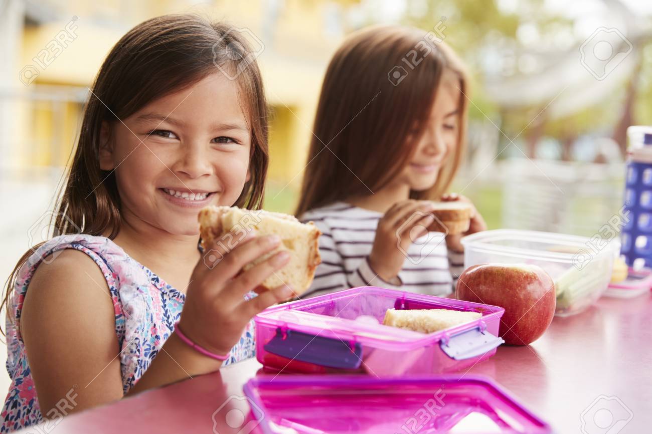 Young schoolgirls holding sandwiches at school lunch table - 109005766 Young schoolgirls holding sandwiches at school lunch table - 109005766