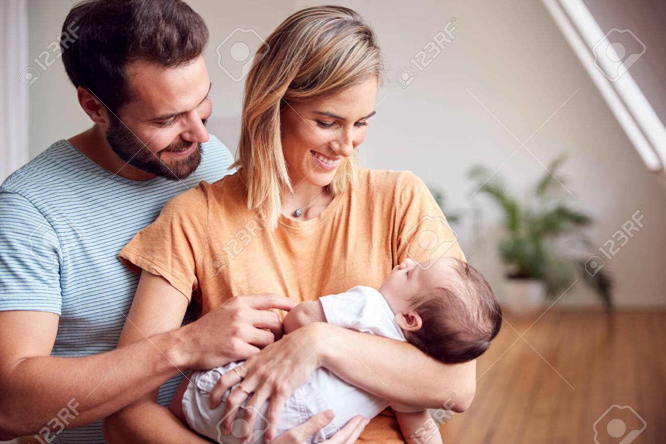 Loving Parents Holding Newborn Baby At Home In Loft Apartment - 124541771 Loving Parents Holding Newborn Baby At Home In Loft Apartment - 124541771