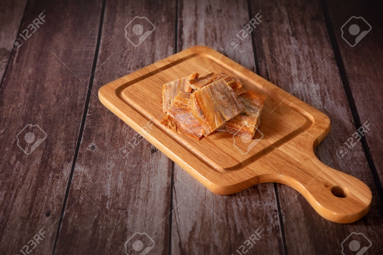 Dried fish fillet on a cutting board with a wooden dark background. Thai food concept. - 166001307 Dried fish fillet on a cutting board with a wooden dark background. Thai food concept. - 166001307