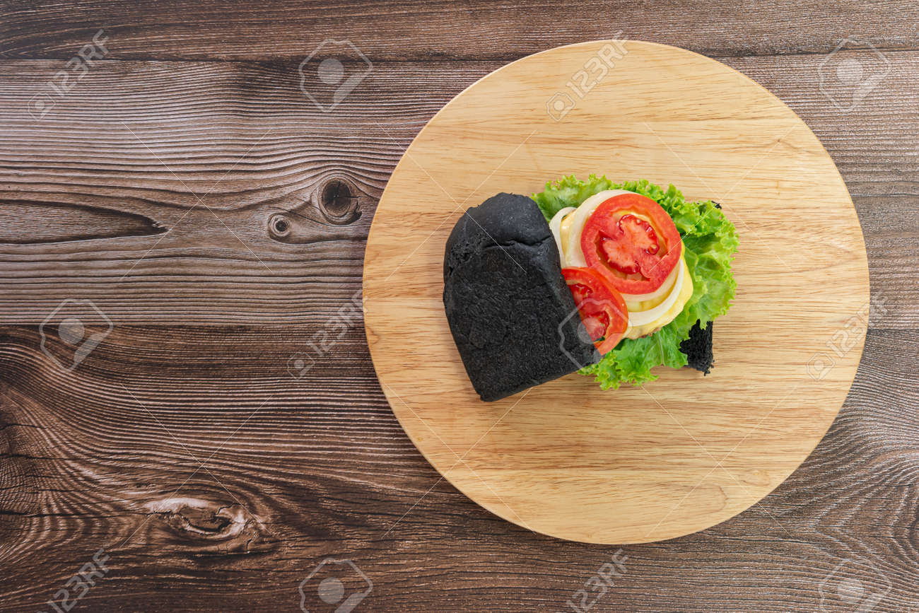 Black bread sandwich on a wooden kitchen board background. Top view. - 166001343 Black bread sandwich on a wooden kitchen board background. Top view. - 166001343