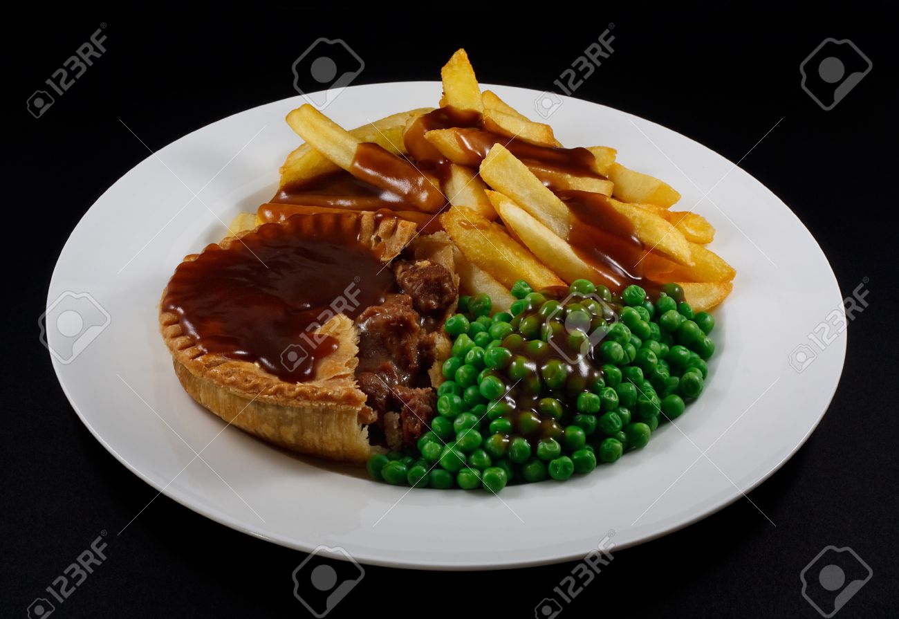 close up of steak pie and chips with peas and gravy a traditional