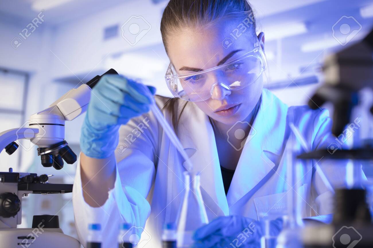 Science research concept. Young scientist during experiment and using microscope in modern laboratory. Glass tubes and beakers. - 144265072 Science research concept. Young scientist during experiment and using microscope in modern laboratory. Glass tubes and beakers. - 144265072