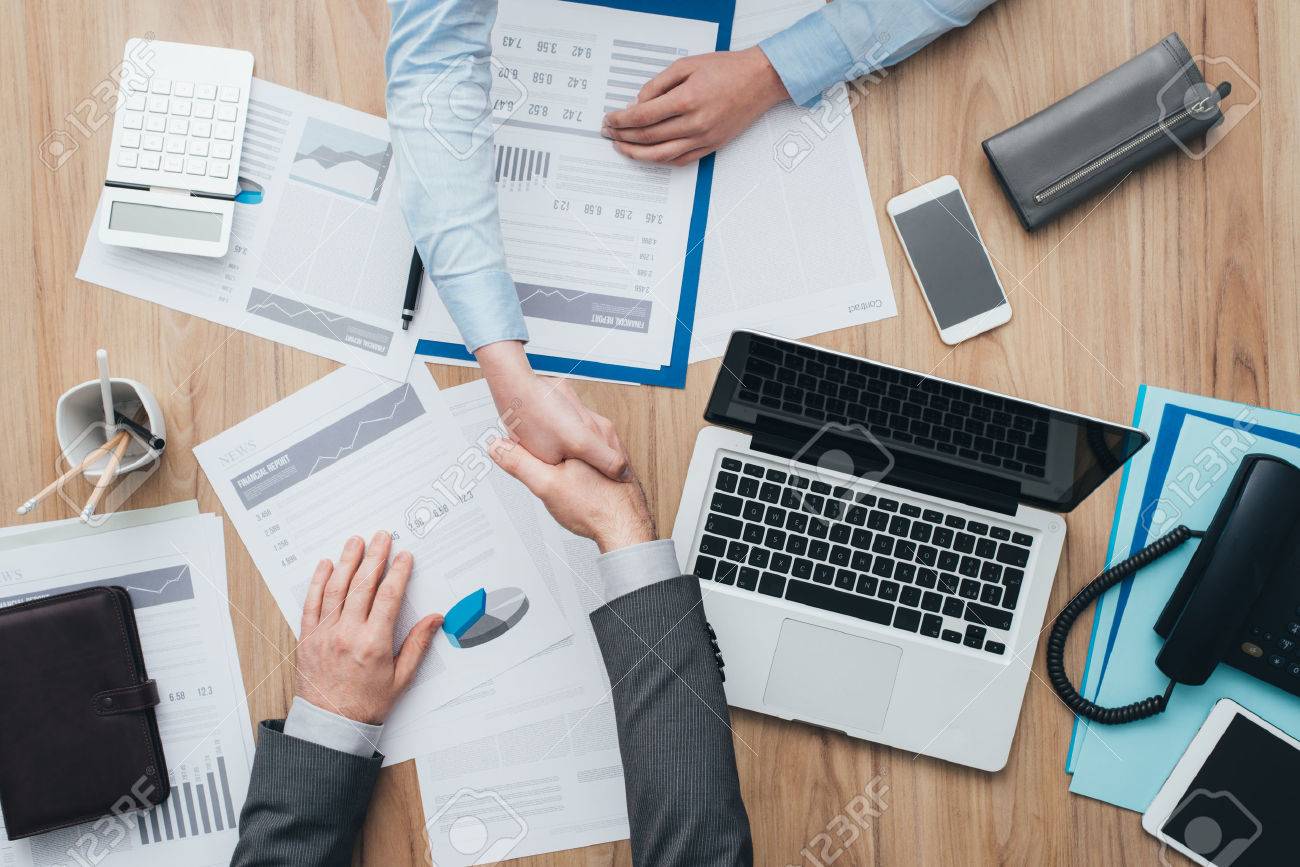 Business people working at office desk and giving an handshake, cooperation and agreement concept - 67009477 Business people working at office desk and giving an handshake, cooperation and agreement concept - 67009477