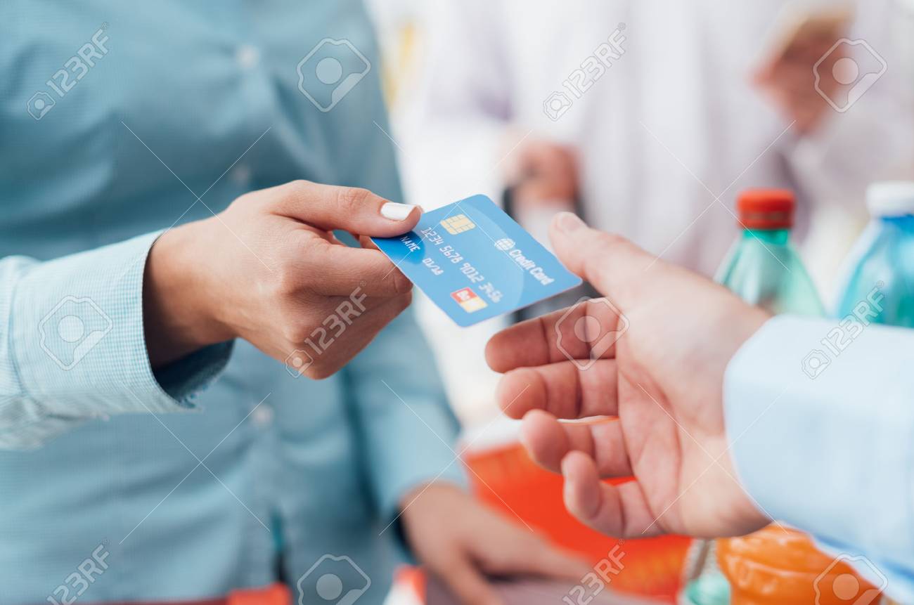 Woman at the supermarket checkout, she is giving her credit card to the cashier, retail and payments concept - 67220940 Woman at the supermarket checkout, she is giving her credit card to the cashier, retail and payments concept - 67220940