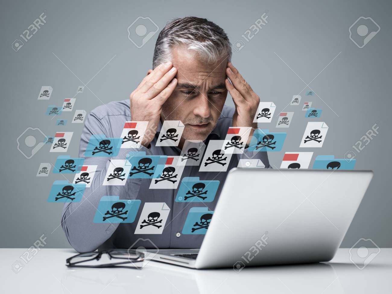 Businessman working with a computer full of viruses, infected files and malwares: he is frustrated with head in hands - 88355487 Businessman working with a computer full of viruses, infected files and malwares: he is frustrated with head in hands - 88355487