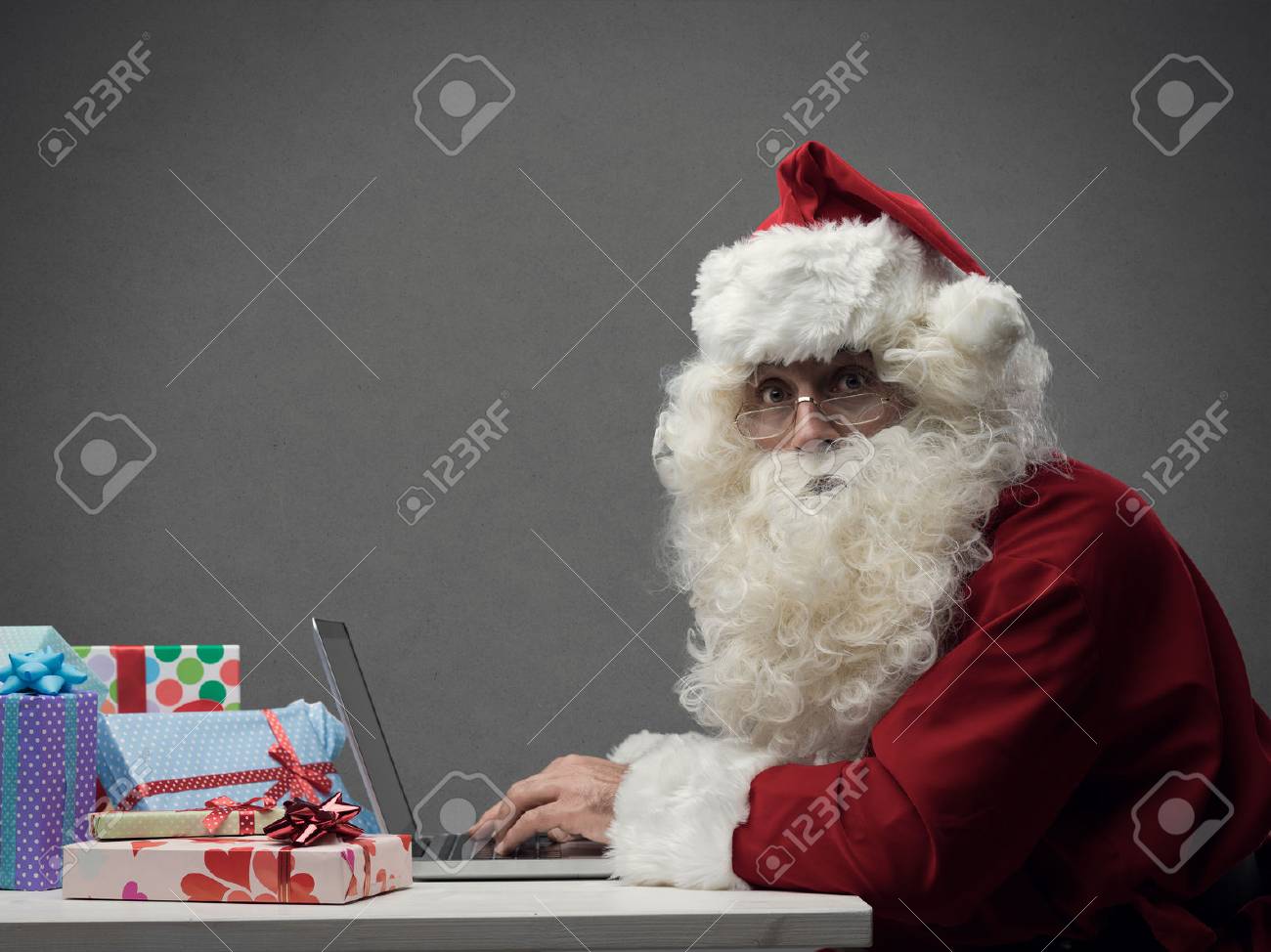 Santa Claus connecting and working online with his laptop, he is preparing gifts and shopping online on Christmas Eve - 89642107 Santa Claus connecting and working online with his laptop, he is preparing gifts and shopping online on Christmas Eve - 89642107
