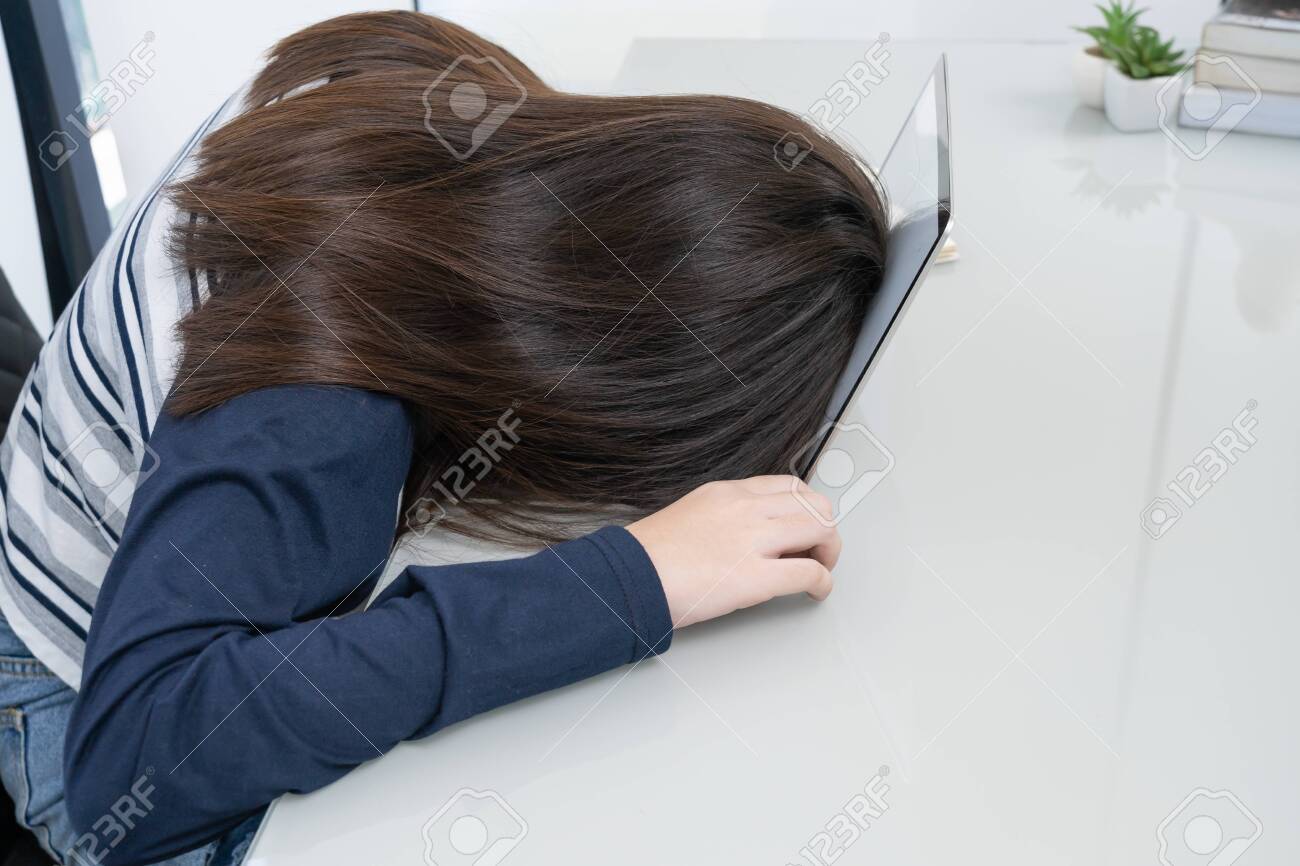 Young woman long hair tired from studying online and fall asleep on desk with laptop - 145877303