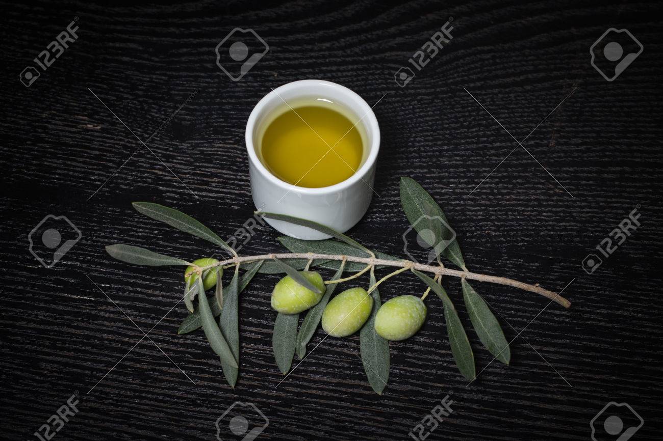 緑のオリーブの実と黒の木製のテーブルやボードに新鮮なオリーブ オイルのキャップがオリーブの木の枝 トーンダウン の写真素材 画像素材 Image