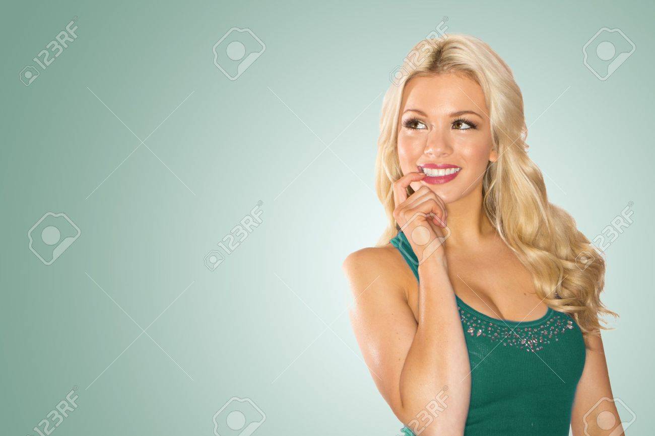 Smiling Pensive Blonde lady with her finger to her mouth looking back in to the frame. - 12586132 Smiling Pensive Blonde lady with her finger to her mouth looking back in to the frame. - 12586132