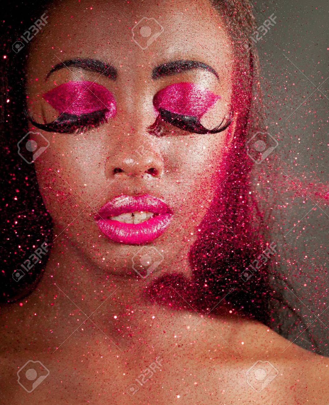 African woman wearing creative magenta makeup with glitter floating past her face. - 12588923 African woman wearing creative magenta makeup with glitter floating past her face. - 12588923