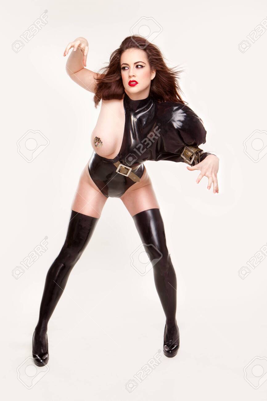 Seductive Woman In Latex Costume And High Heels Posing Over White Studio  Wall Background Stock Photo, Picture and Royalty Free Image. Image  126261587.
