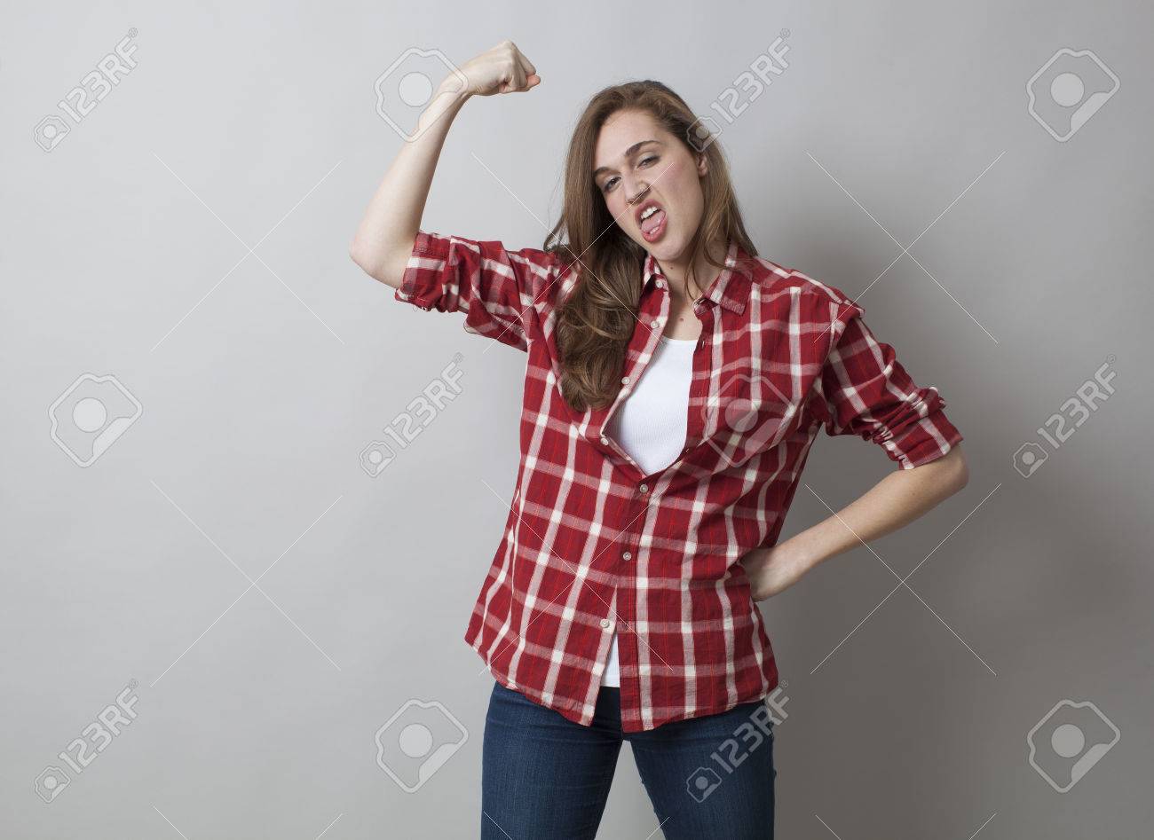 女の子パワー コンセプト 男のような若いブルネット演技愚かな 女性的な独立 スタジオ撮影のため彼女のたくましい腕を示す の写真素材 画像素材 Image