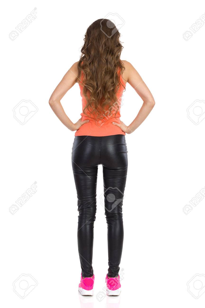 オレンジ色のシャツ 革のズボンの腰に手で立っている女性の後ろ姿 完全な長さのスタジオ撮影に分離白 の写真素材 画像素材 Image
