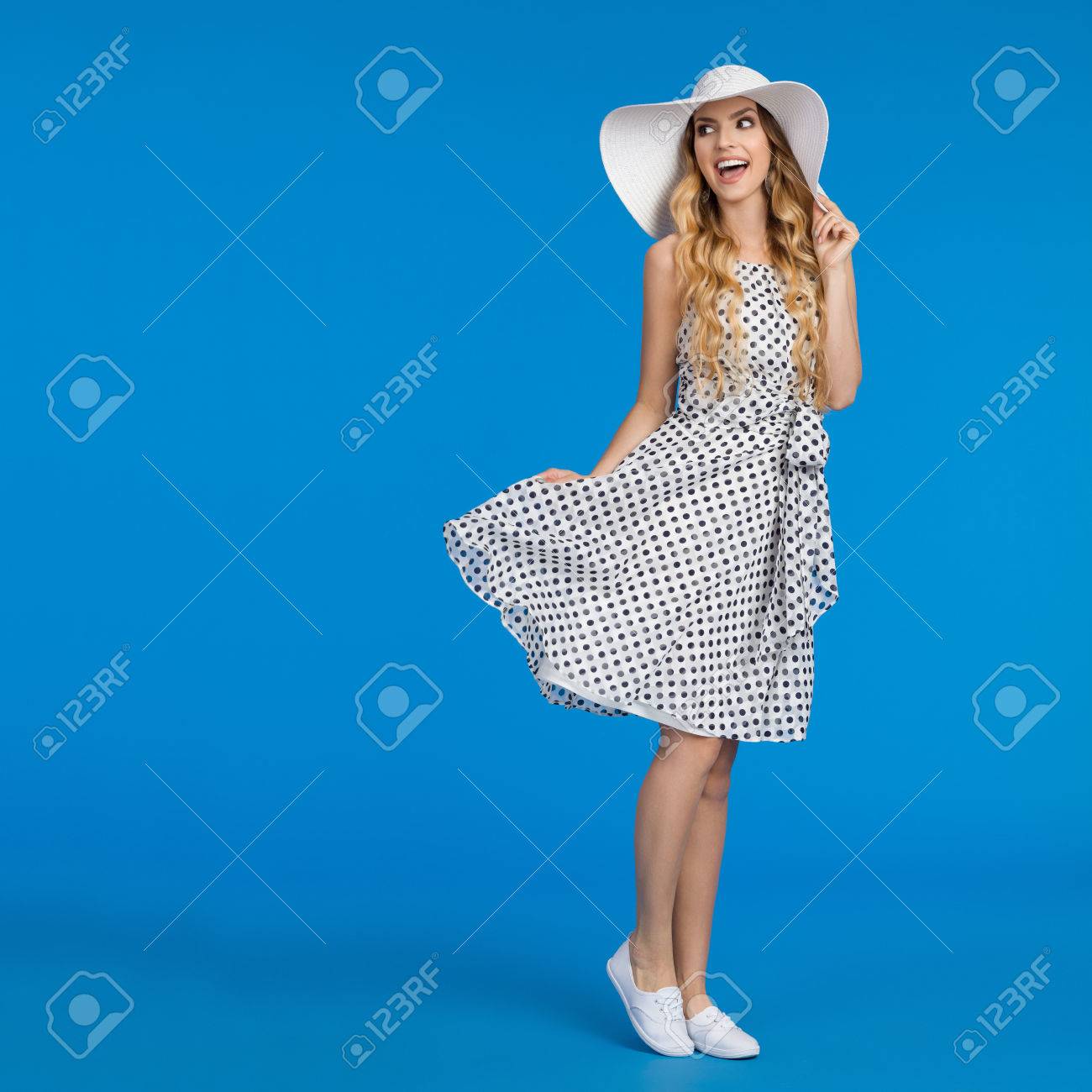 白点線の夏ワンピース スニーカーと帽子の美しい若い女性が肩や叫びを離れています 完全な長さのスタジオは 青の背景に撮影 の写真素材 画像素材 Image