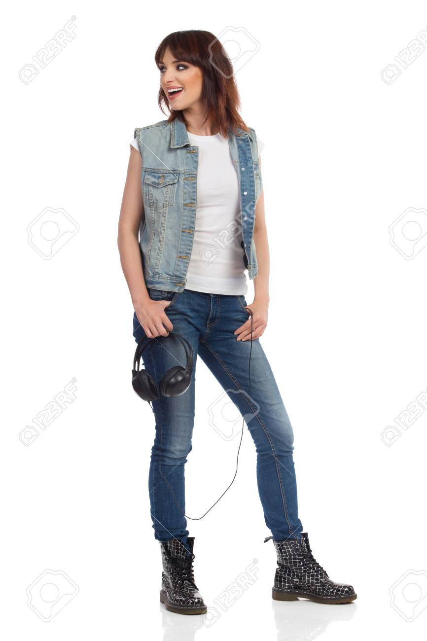 La Mujer Joven Feliz En Chaleco De Los Pantalones Vaqueros Y Los pantalones vaqueros y las botas de mujer Fotografía de