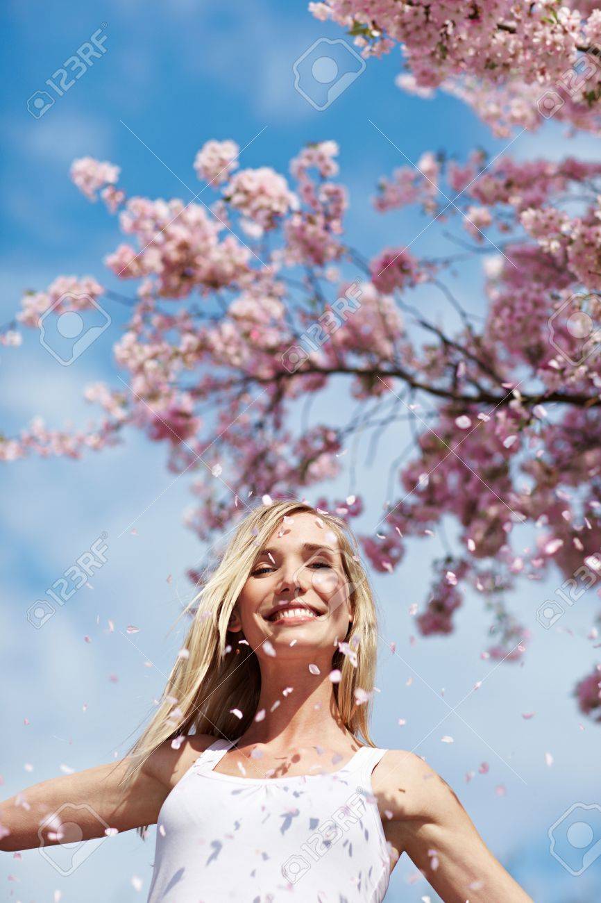 Young woman throwing pink cherry blossoms in the air - 6857964 Young woman throwing pink cherry blossoms in the air - 6857964