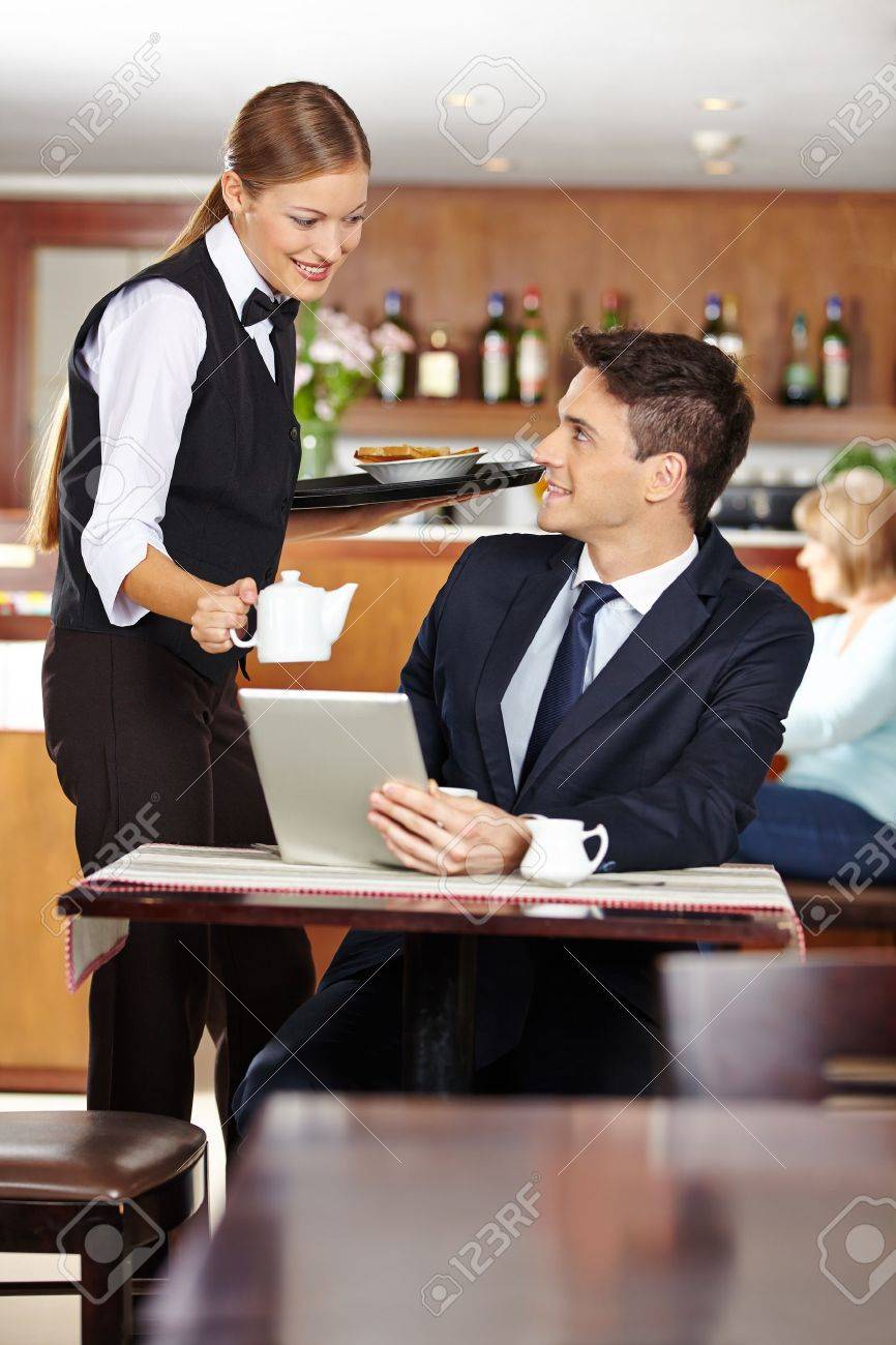 Female Waiter Serving Businessman In Coffee Shop A Pot Of Coffee ...