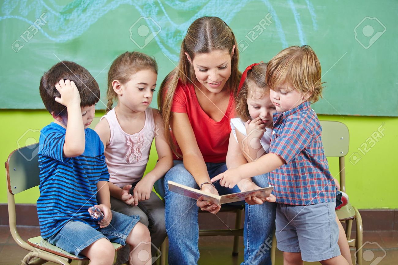 children and nursery teacher reading book together in kindergarten nursery teacher