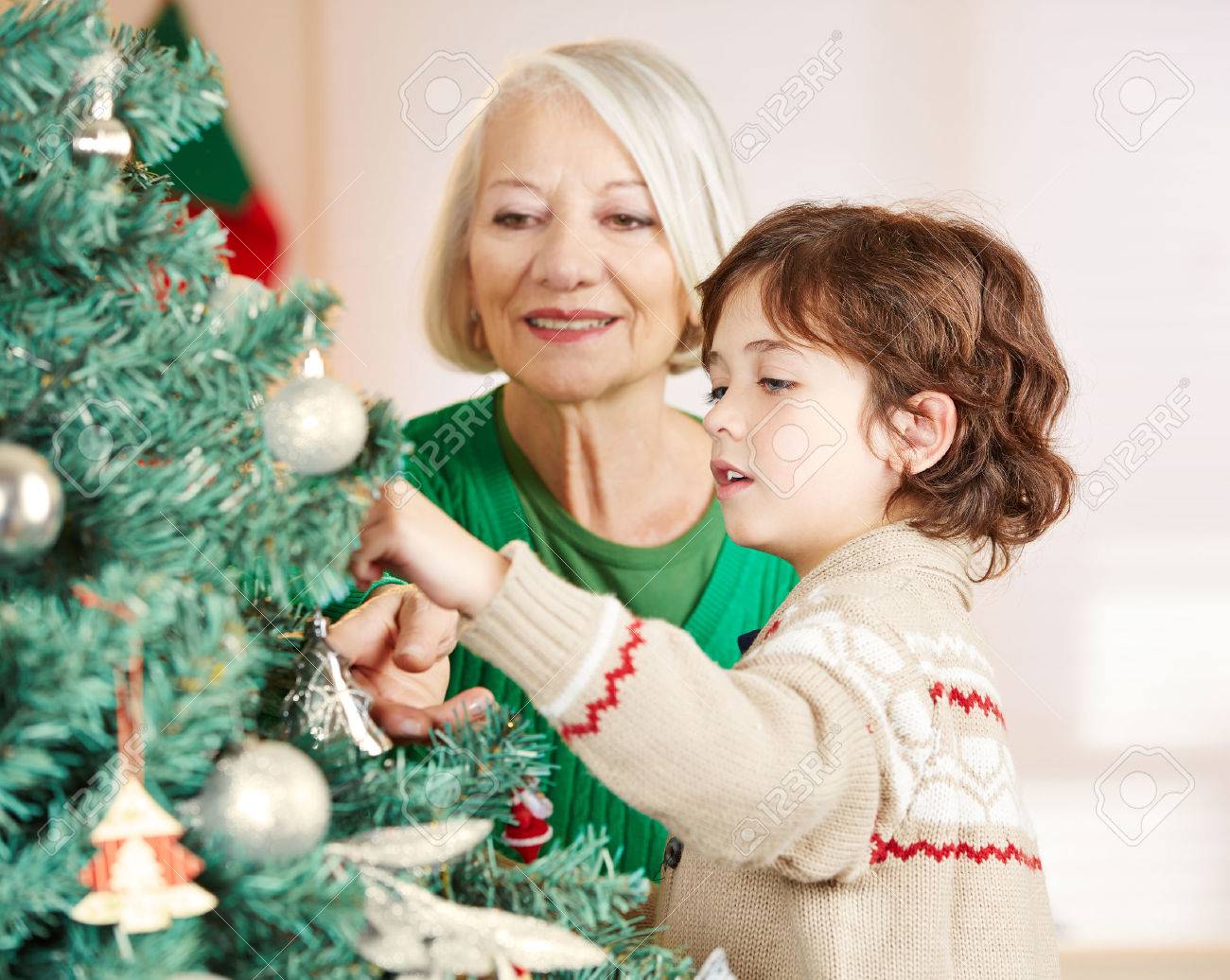 grandmother and grandchild decorating christmas tree at home stock