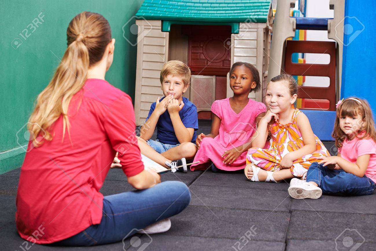 discussion group of children in kindergarten talking to nursery nursery teacher