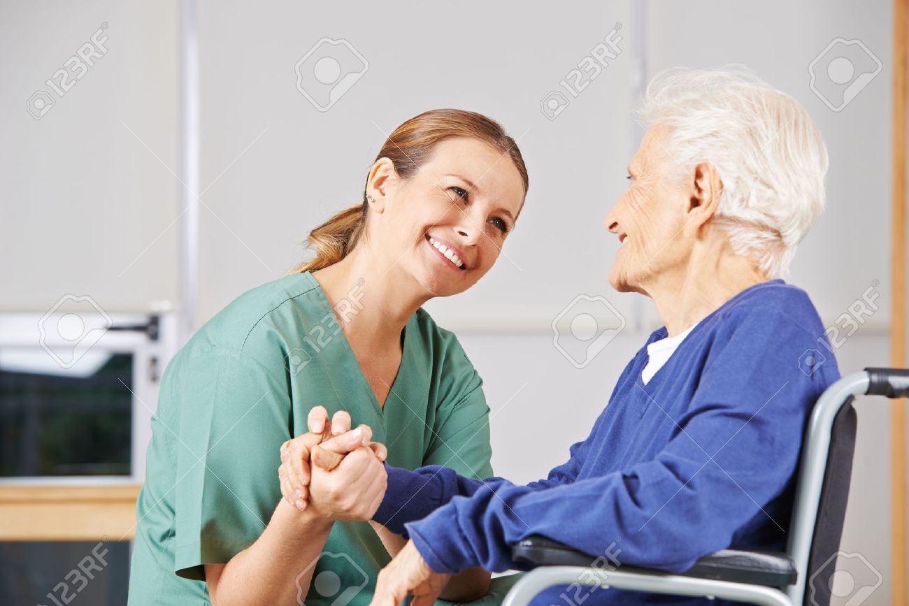 Happy geriatric nurse holding hands with senior woman in a wheelchair - 52996461 Happy geriatric nurse holding hands with senior woman in a wheelchair - 52996461