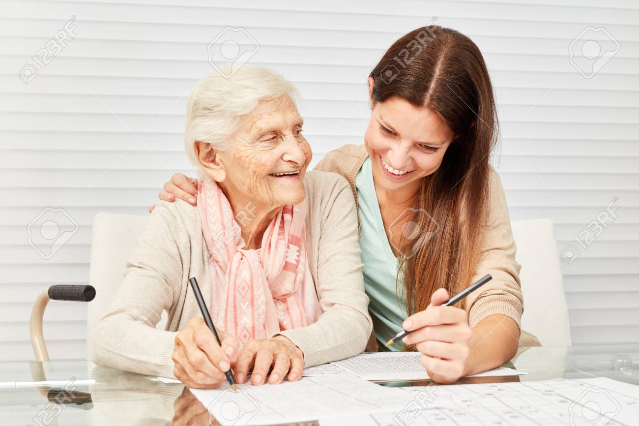 Girls as a caring grandson and senior together solve puzzles in retirement home - 93942485 Girls as a caring grandson and senior together solve puzzles in retirement home - 93942485