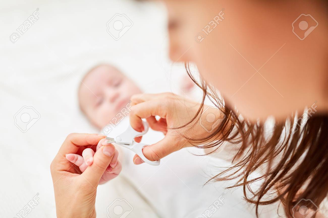 With care and caution mother cuts the fingernails of an infant - 106556642 With care and caution mother cuts the fingernails of an infant - 106556642