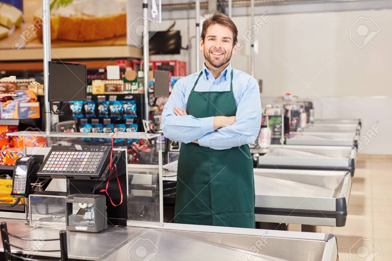 Smiling Cashier Or Salesman In Green Apron At The Supermarket Cashier Stock  Photo, Picture And Royalty Free Image. Image 130131002.
