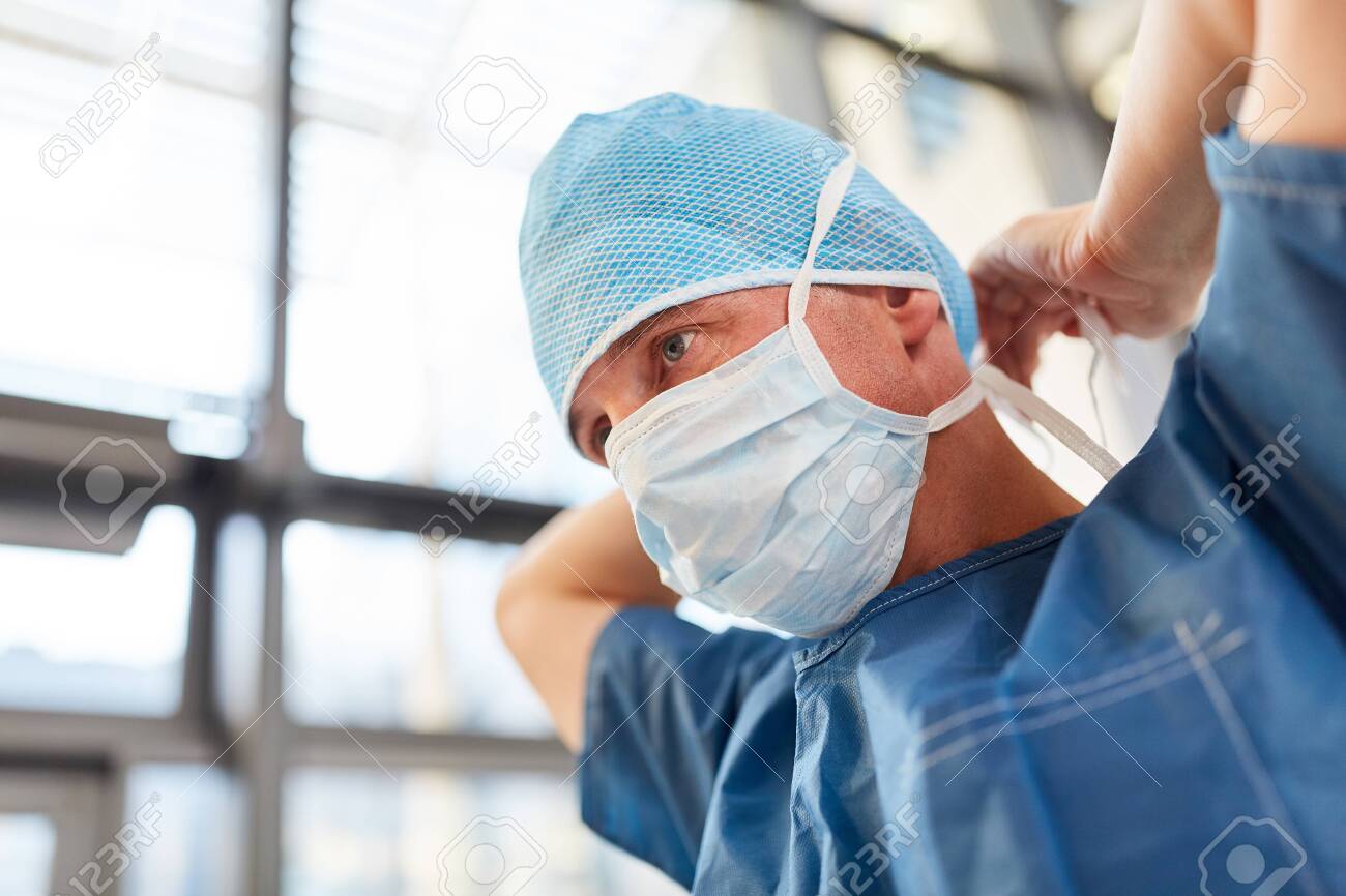 Surgeon in blue surgical gown binds the mouthguard for an emergency - 131352581 Surgeon in blue surgical gown binds the mouthguard for an emergency - 131352581