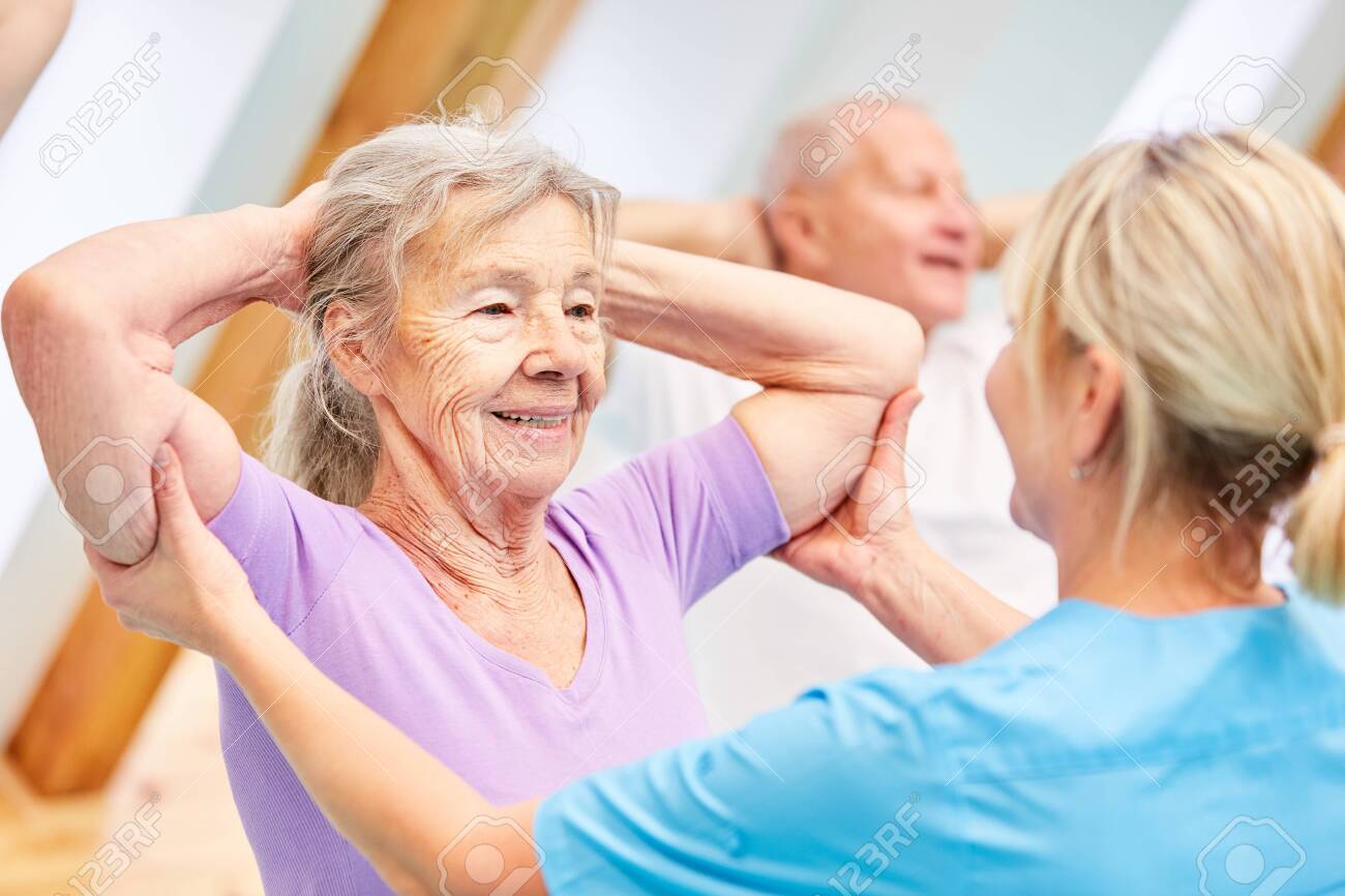 Trainer helps seniors with healthy back training in physiotherapy - 151488897 Trainer helps seniors with healthy back training in physiotherapy - 151488897