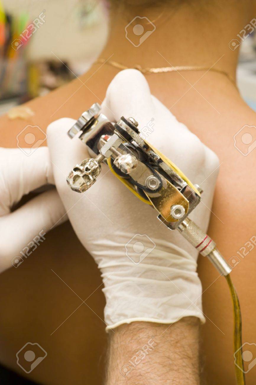 In the tattoo salon. Tattoo master tattooing on the a girl back. - 12728845 In the tattoo salon. Tattoo master tattooing on the a girl back. - 12728845