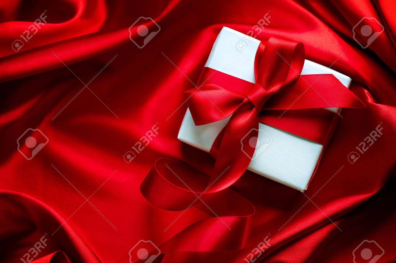 Valentine gift box with red satin ribbon on red silk background - 51849723 Valentine gift box with red satin ribbon on red silk background - 51849723