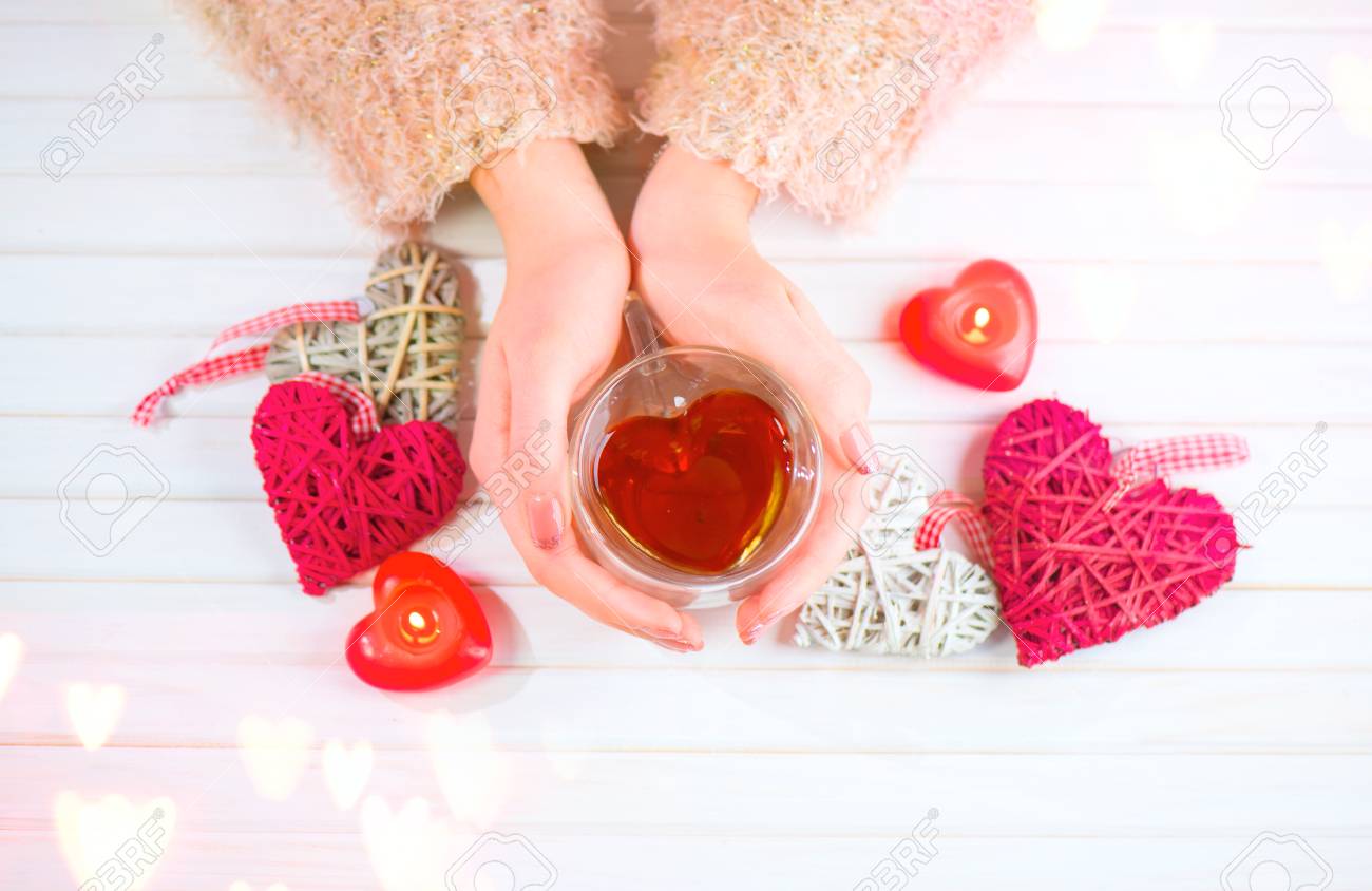 St. Valentine's Day. Young woman hands holding heart shaped tea cup over wooden background. Love concept. Top view - 94662298 St. Valentine's Day. Young woman hands holding heart shaped tea cup over wooden background. Love concept. Top view - 94662298