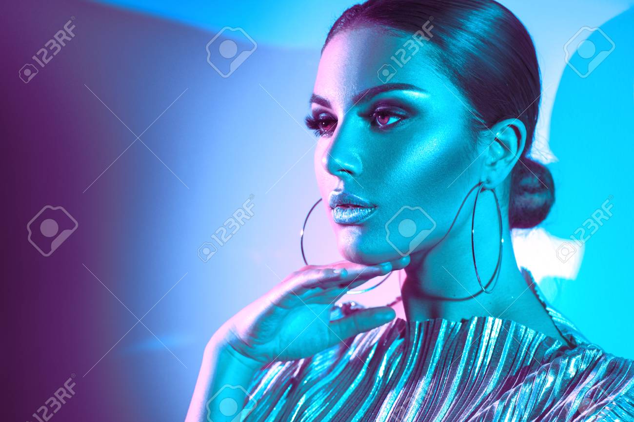 Fashion model brunette woman in colorful bright neon lights posing in studio. Beautiful girl, trendy glowing makeup, metallic silver lips - 104315276 Fashion model brunette woman in colorful bright neon lights posing in studio. Beautiful girl, trendy glowing makeup, metallic silver lips - 104315276